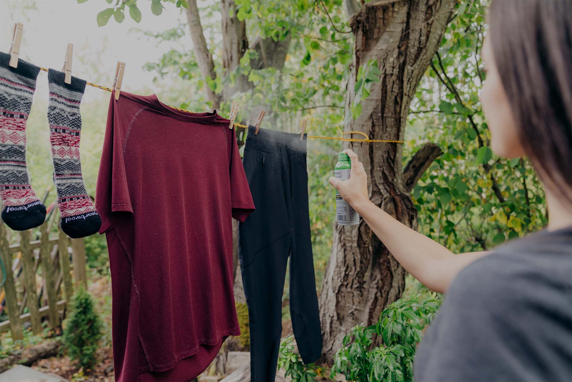 Woman treating clothes with permethrin spray.